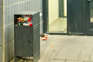 Bahçedeki çöp bidonları. Bir apartmanın girişinde taşan bir vazo..