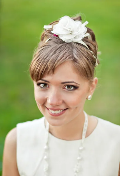 Beautiful young bride standing in a park and smiling — Stock Photo, Image