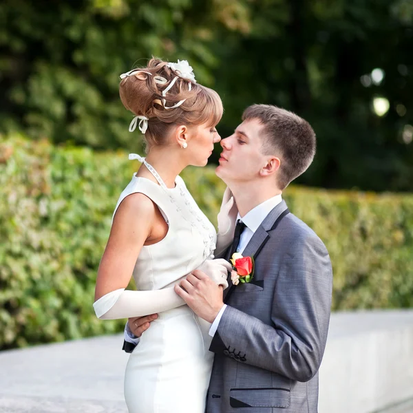 Bride and groom standing in a park — Stock Photo, Image