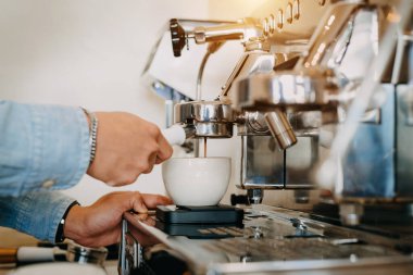 Yakın plan profesyonel kahve imalatı. Restorandaki kahve makinesinden seramik bardaklara dökülen espresso 'nun yan görüntüsü.