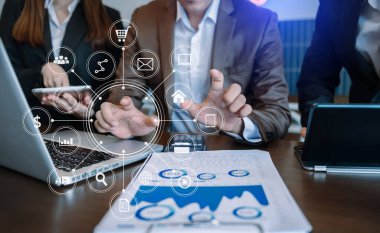 İş ortakları toplantısı konsepti. Ofiste bilgisayar, tablet ve akıllı telefon kullanan bir iş adamı. Sanal simge ekranında sabahları dijital pazarlama mobil uygulaması