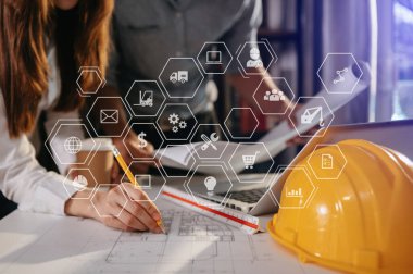 Çalışma ve tablet hakkında konuşan iki meslektaş, ofisteki inşaat alanında mimari projeyle ilgili bilgisayarı açtılar.