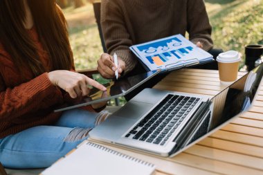 Akıllı telefon, dizüstü bilgisayar ve dijital tabletle parkta çalışan iki işadamı