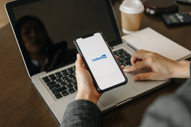  Chiang Mai Tayland. 02 Mart 2022: Bir kadın Apple iPhone 11 'i ekranda LinkedIn uygulaması ile maksimum düzeyde tutuyor. LinkedIn akıllı telefonlar için fotoğraf paylaşım uygulaması.
