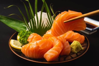 Sashimi, Somon, Japon yemek çubukları ve siyah masada wasabi.
