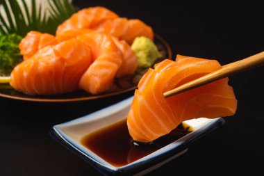 Sashimi, Somon, Japon yemek çubukları ve siyah masada wasabi.