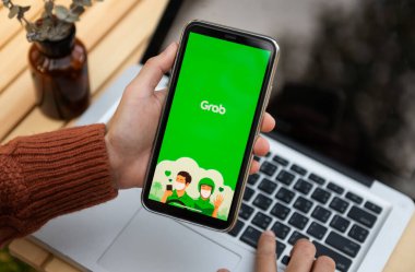 Chiang Mai Tayland. 25 Mart 2022: Bir MAN el ele tutuşması uygulaması iphone 'da bilgisayar dizüstü bilgisayarı ve kahve dükkanındaki kulak temizleme tahtası ile maksimum 11 pro gösteriliyor. Yakalama akıllı telefon uygulaması tabanlı ulaşım ağı