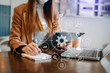 İş kadını ya da tasarımcı, bilgisayarlı ve dijital tablet bilgisayarlı cep telefonu ve sanal simge ağı şeması olan bir belge kullanıyor.