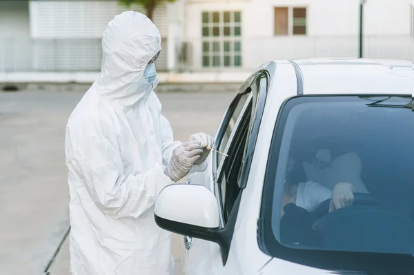 Medical worker in protective suit screening woman Driver to Sampling secretion to check for Covid-19.