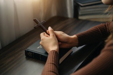 Oturan ve kutsal kitabı okuyan bir kadın. Ellerindeki tahta haç. Hıristiyan eğitimi kutsal yazıtların açılıp Tanrı 'ya dua etmesini sağlar.