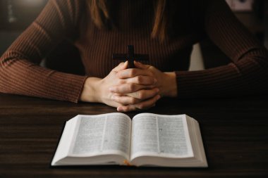 Oturan ve kutsal kitabı okuyan kadın. Ellerindeki tahta haç. Hıristiyan eğitimi Kutsal Yazıtlar 'ın açılışıdır.