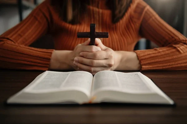 Woman sitting and studying the scriptures.The  wooden cross in the hands. Christian education concepts The Holy Scriptures open