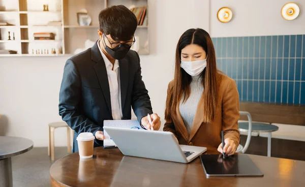 Two asia business working together with laptop on office desk in office room sitting at modern offic