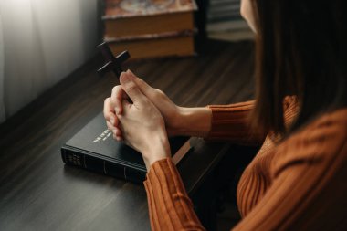 Oturan ve kutsal kitabı okuyan kadın. Ellerindeki tahta haç. Hıristiyan eğitimi Kutsal Yazıtlar 'ın açılışıdır. 