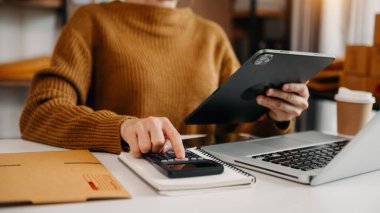 Dizüstü bilgisayar, akıllı telefon, tablet kullanan ve iş yerinde online alışveriş yapan bir kadın. Evde.