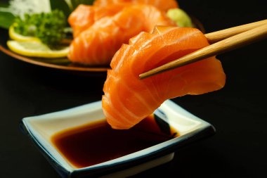 Sashimi, Somon, Japon yemek çubukları ve siyah masada wasabi.