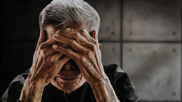 старший азиат прикрывает лицо руками. Депрессия и тревога