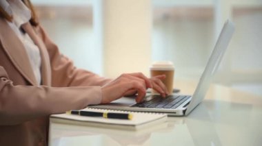 Masadaki iş kadını dizüstü bilgisayar kullanıyor, klavyede daktilo kullanıyor. 