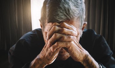 Yaşlı adam elleri, kederi ve depresyonu ile yüzünü kapatıyor.