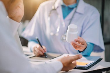 Doktor reçete yazıyor ve ilaç tutuyor. 