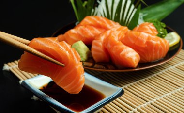 holding delicious salmon fish slice with chopsticks, Asian seafood 