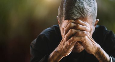 Yaşlı adam elleri, kederi ve depresyonu ile yüzünü kapatıyor.