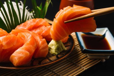holding delicious salmon fish slice with chopsticks, Asian seafood 
