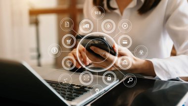 Dizüstü bilgisayar ve iş yerlerinde çalışırken cep telefonu kullanan bir kadın 