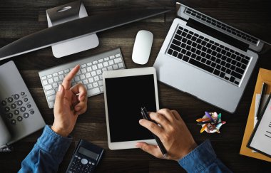 Erkek eli, bilgisayar monitörü, klavye ve telefonu olan ofis masasının üst görüntüsü