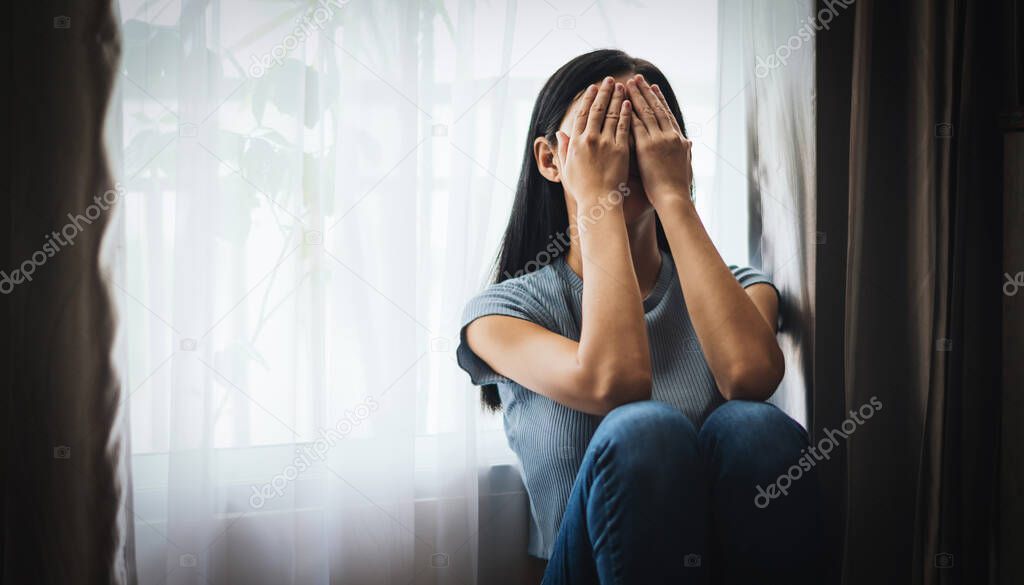 crying woman in Depression covering face with hands while sitting on floor at home 