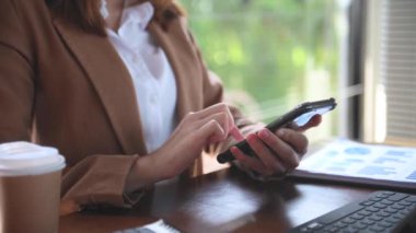 businesswoman using mobile phone at desk with laptop 