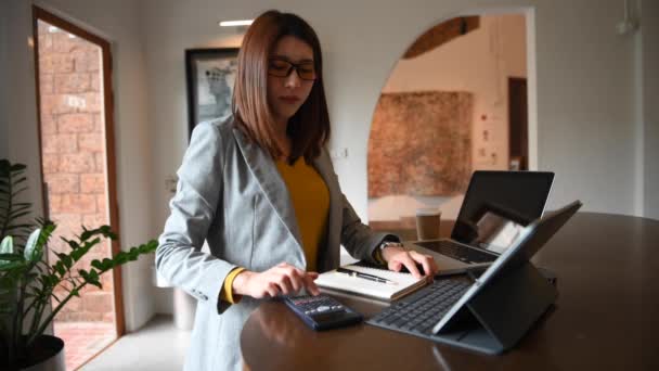 Азіатська Бізнес Леді Використовує Калькулятор Офісному Столі Ноутбуком Цифровим Планшетом — стокове відео