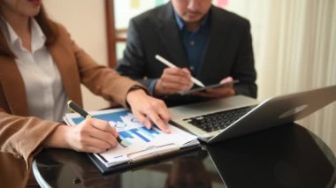 businesswoman at desk with folder, document financial graph, man using tablet and laptop  