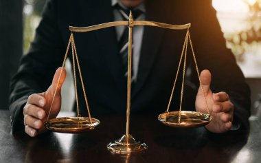 lawyer man in black suit with brass scale on wooden table. justice concept 