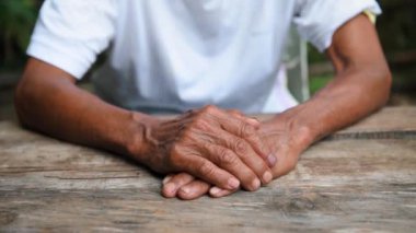 Hands of the old man and woman on the wooden table 