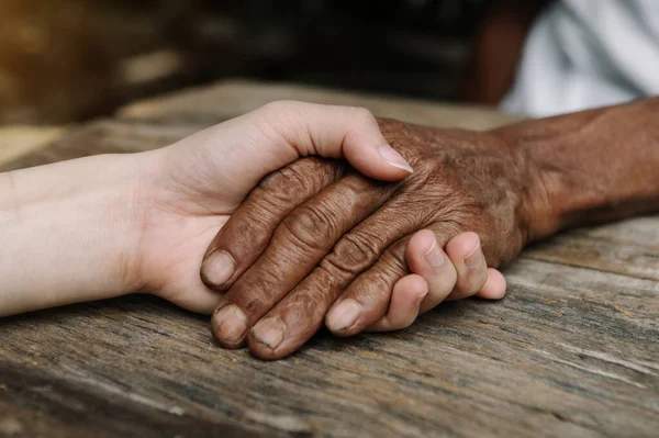 Hands of old man and young woman together