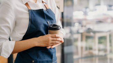 Coffee Business Concept. Beautiful lady offers disposable take away coffee at the coffee shop