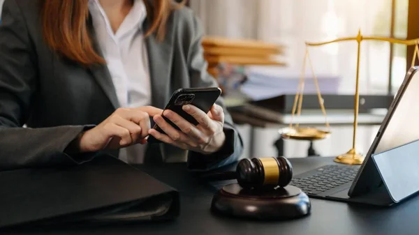 justice and law concept. Female lawyer in a courtroom with the gavel, working with smartphone