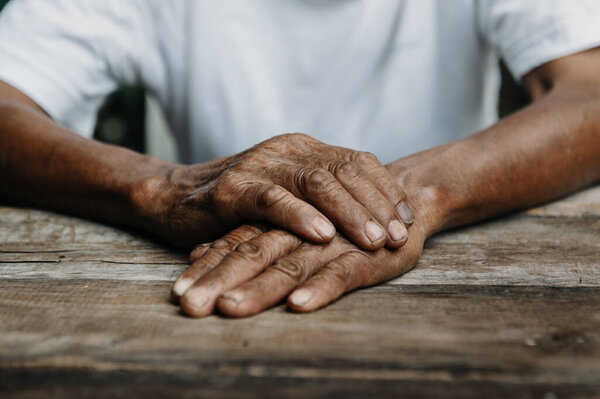Hands of old man on wooden table 
