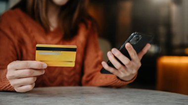 Cep telefonunda online alışveriş için kredi kartı tutan kadın elleri 