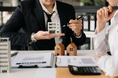 Emlak komisyoncusu sunar ve müşteri kadına danışır. 