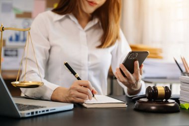 İş kadınının cep telefonu ve kağıt üzerine kalem notları kullanarak yazması kısmi görünüm 