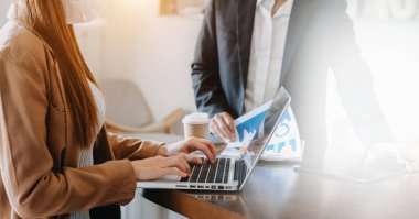 İş arkadaşları birlikte çalışıyor, tartışıyorlar ve ofiste mali belgeli tablet ve dizüstü bilgisayar kullanıyorlar. 