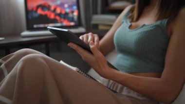 Evden çalışıyorum. Çalışan bir kadının, evdeki kanepede otururken dijital tablet kullanmasının kısmi görüntüsü 