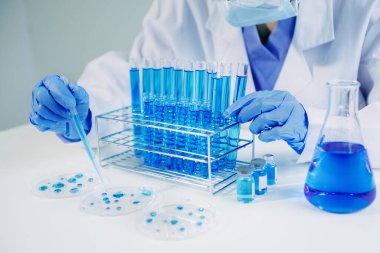 Kimya laboratuvarında kimyasal sıvıları karıştıran bir bilim adamı. Kimya laboratuvarında çalışan bir araştırmacı, tüplerde mavi sıvı. 