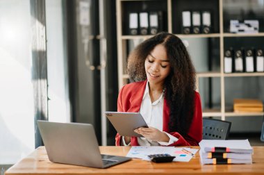 Young beautiful woman using laptop and tablet while sitting at her working place. Concentrated at work