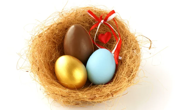 Gold, chocolate and blue eggs in the nest — Stock Photo, Image