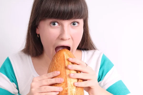 Hezká dívka drží a kousání bochník chleba — Stock fotografie