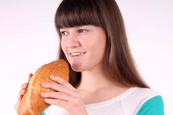 Bonita chica sosteniendo y mordiendo pan — Foto de Stock