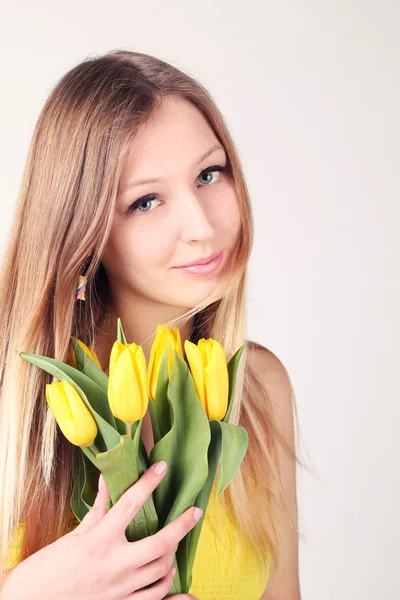 Blonde met gele tulpen — Stockfoto